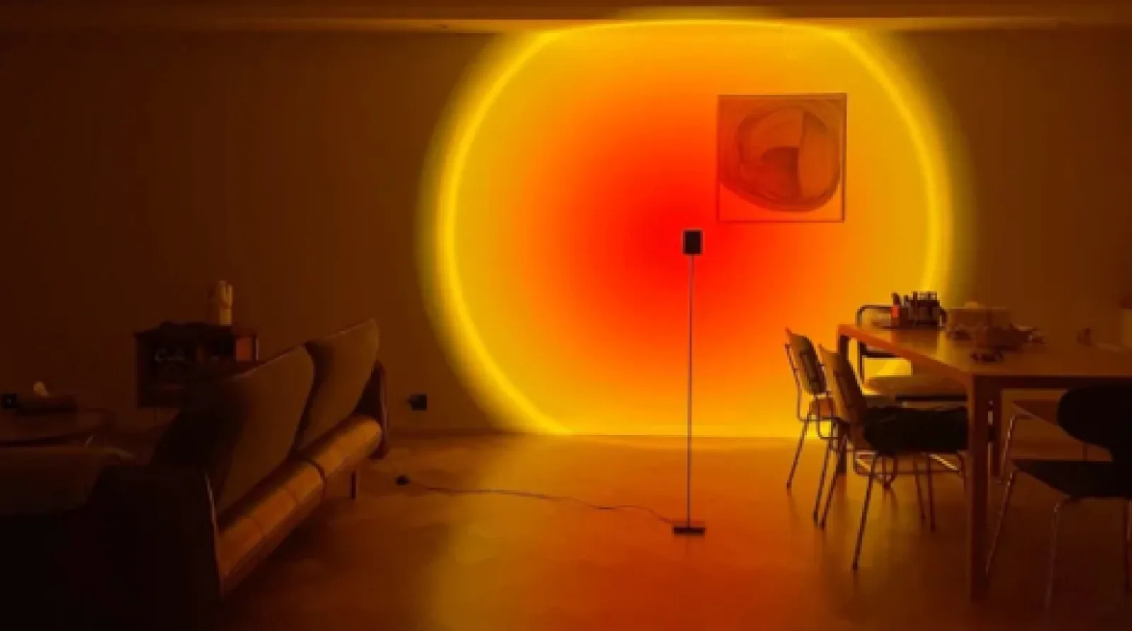 The same lamp projecting onto a wall where a framed picture sits inside the disc, breaking the circle with a hard rectangular edge.